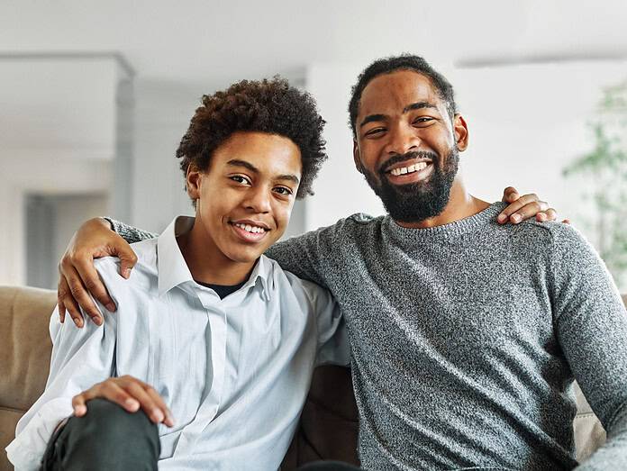 Portrait of a happy teenage boy son and his father at home. Sharing secrets and having fun, support and parenthood concept