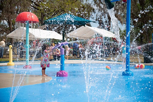 A little girl operates a water cannon at the grand opening of the splash pad at Tom Varn Park on March 1, 2025. [Photo by Jenifer Truitt]