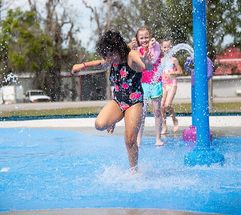 Children laugh and shriek as they run through the cold water at the grand opening of the splash pad at Tom Varn Park on March 1, 2025. [Photo by Jenifer Truitt]