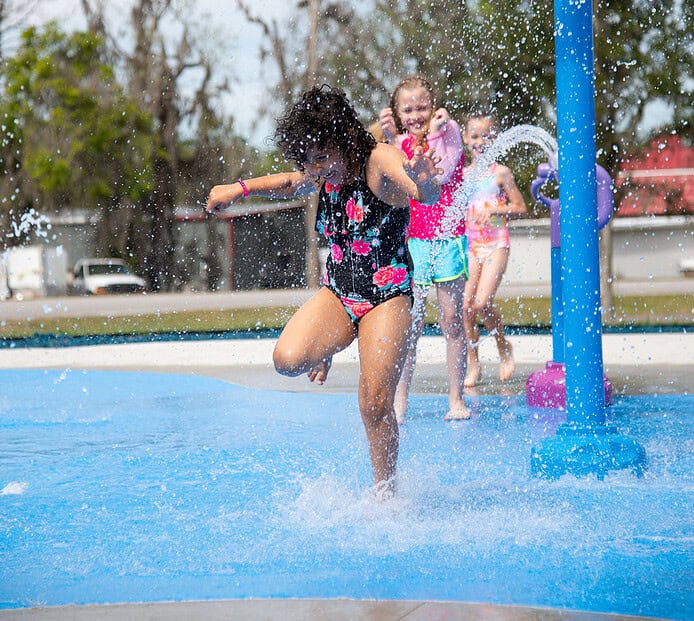 Children laugh and shriek as they run through the cold water at the grand opening of the splash pad at Tom Varn Park on March 1, 2025. [Photo by Jenifer Truitt]