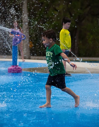 A little boy runs through the water at the grand opening of the splash pad at Tom Varn Park on March 1, 2025. [Photo by Jenifer Truitt]