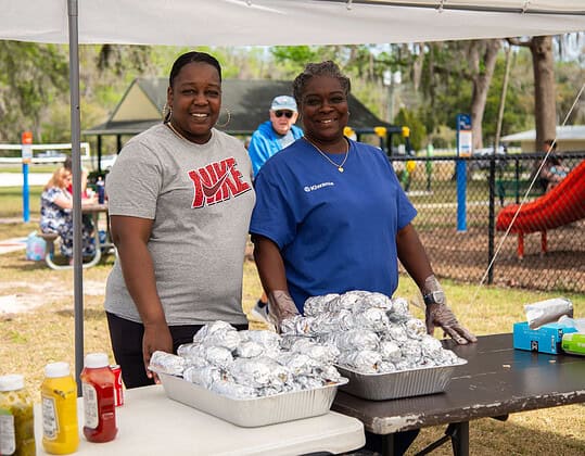 Event volunteers Kenya Pickering with Habitat for Humanity (left) and Kiwanis member Elsie White (right) serve lunch to visitors during the grand opening of the Tom Varn Park splash pad on March 1, 2025. [Photo by Jenifer Truitt]