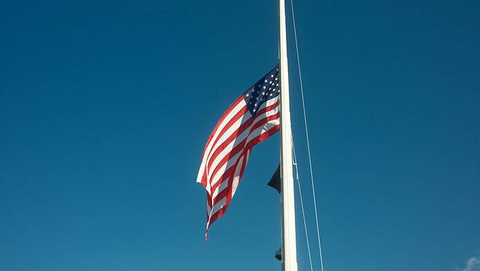 American Flag at Half Mast Against Clear Blue Sky