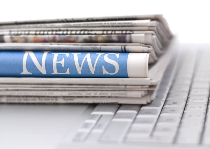 Stack of newspapers resting on laptop keyboard